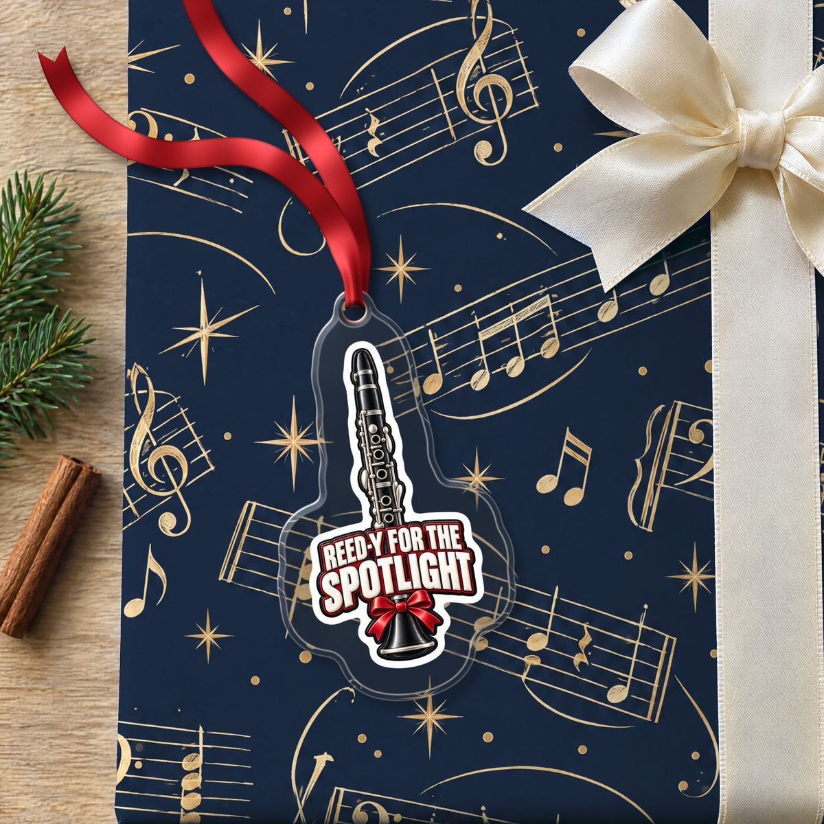Reed-y for the Spotlight Clarinet clear acrylic Christmas ornament lying on a gift wrapped in Rhythm and Beat music wrapping paper