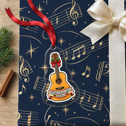 Guitar Player 2026 clear acrylic Christmas ornament lying on a gift wrapped in Rhythm and Beat music wrapping paper