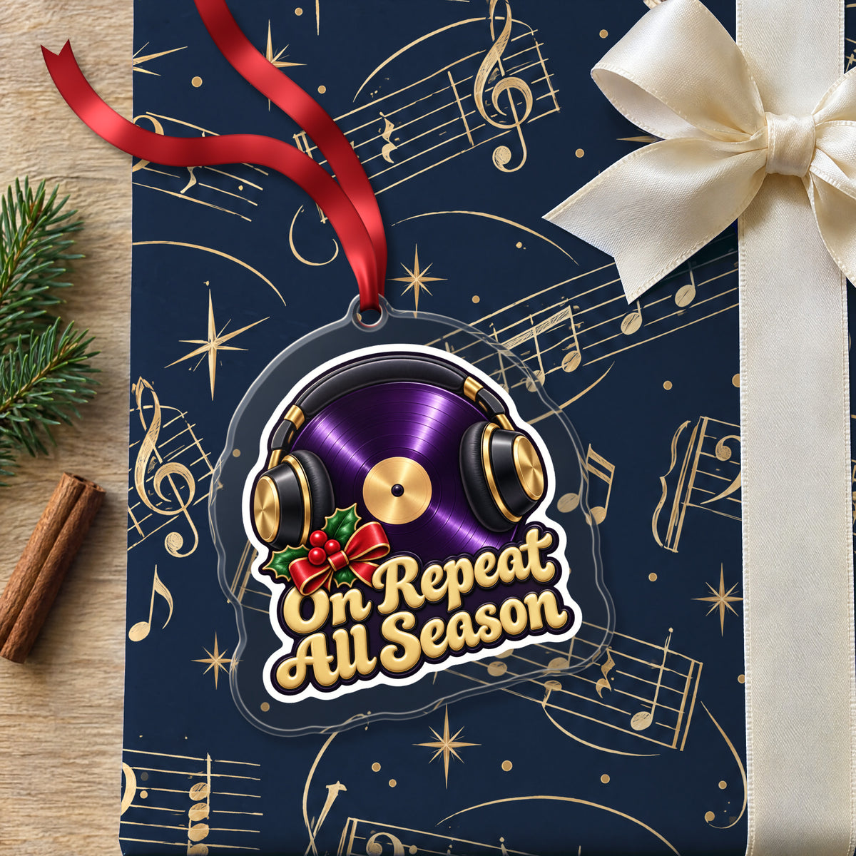 On Repeat Vinyl and Headphones clear acrylic Christmas ornament lying on a gift wrapped in Rhythm and Beat music wrapping paper