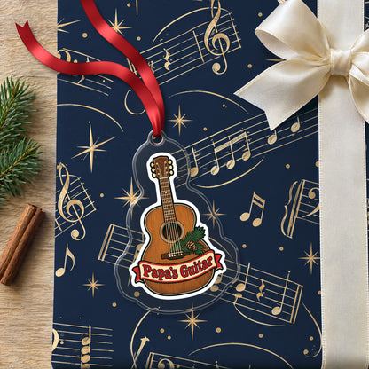 Papa's Guitar Christmas Ornament for Grandpa clear acrylic Christmas ornament lying on a gift wrapped in Rhythm and Beat music wrapping paper