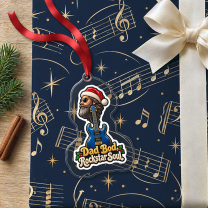 Dad Bod, Rockstar Soul Guitar clear acrylic Christmas ornament lying on a gift wrapped in Rhythm and Beat music wrapping paper