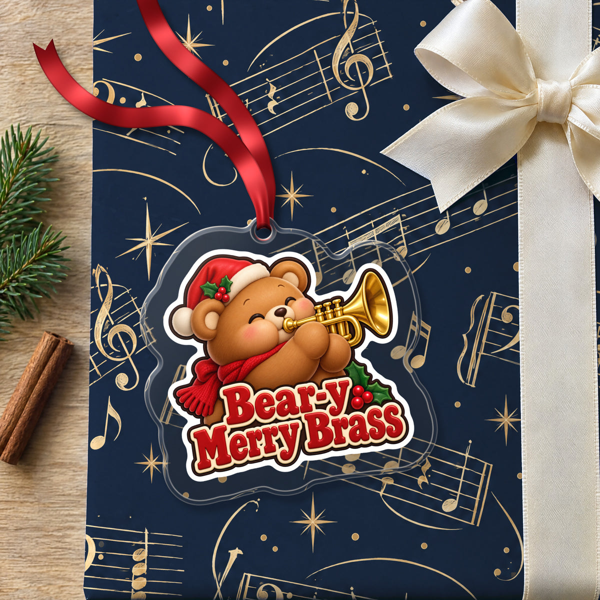 Bear-y Merry Brass Teddy Bear Trumpet clear acrylic Christmas ornament lying on a gift wrapped in Rhythm and Beat music wrapping paper