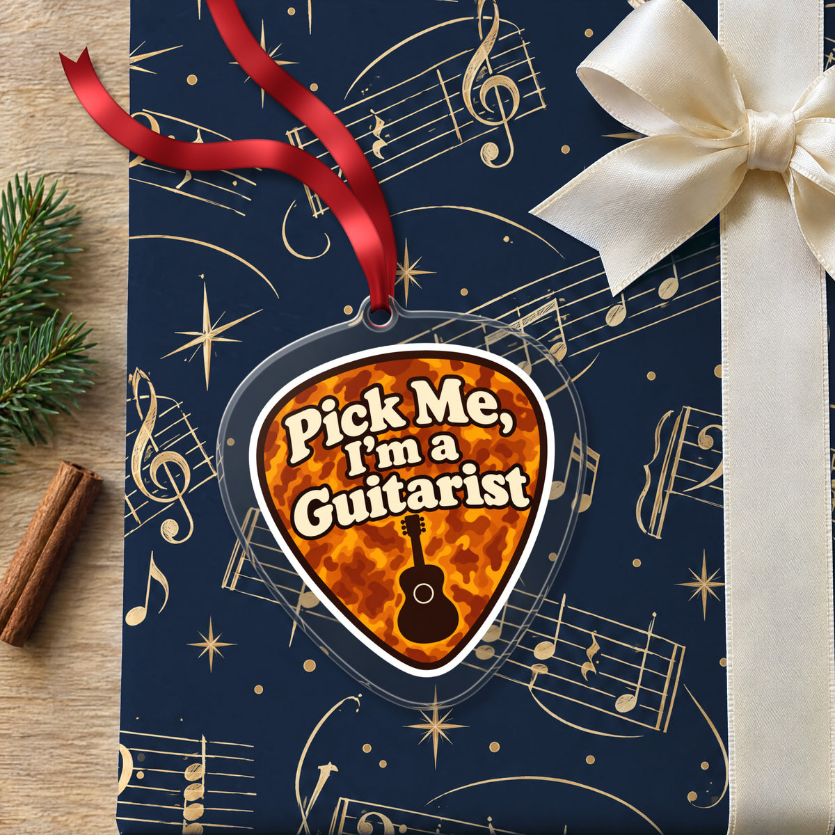 Pick Me, I'm a Guitarist Guitar Pick clear acrylic Christmas ornament lying on a gift wrapped in Rhythm and Beat music wrapping paper