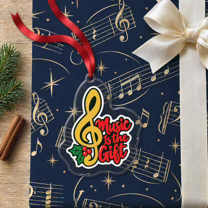 Music Is the Gift Treble Clef clear acrylic Christmas ornament lying on a gift wrapped in Rhythm and Beat music wrapping paper