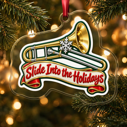 Slide Into the Holidays Trombone clear acrylic Christmas ornament hanging on a lit Christmas tree with warm gold lights