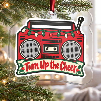 Turn Up the Cheer Boombox clear acrylic Christmas ornament hanging on a Christmas tree by a bright window