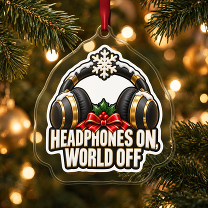 Headphones On, World Off clear acrylic Christmas ornament hanging on a lit Christmas tree with warm gold lights