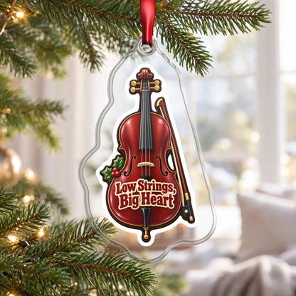 Low Strings, Big Heart Cello clear acrylic Christmas ornament hanging on a Christmas tree by a bright window