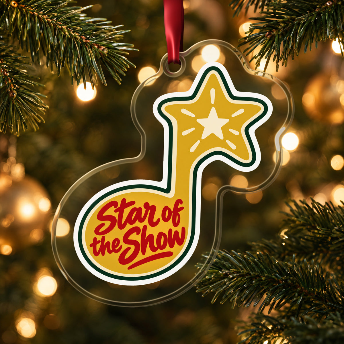 Star of the Show Music Note clear acrylic Christmas ornament hanging on a lit Christmas tree with warm gold lights
