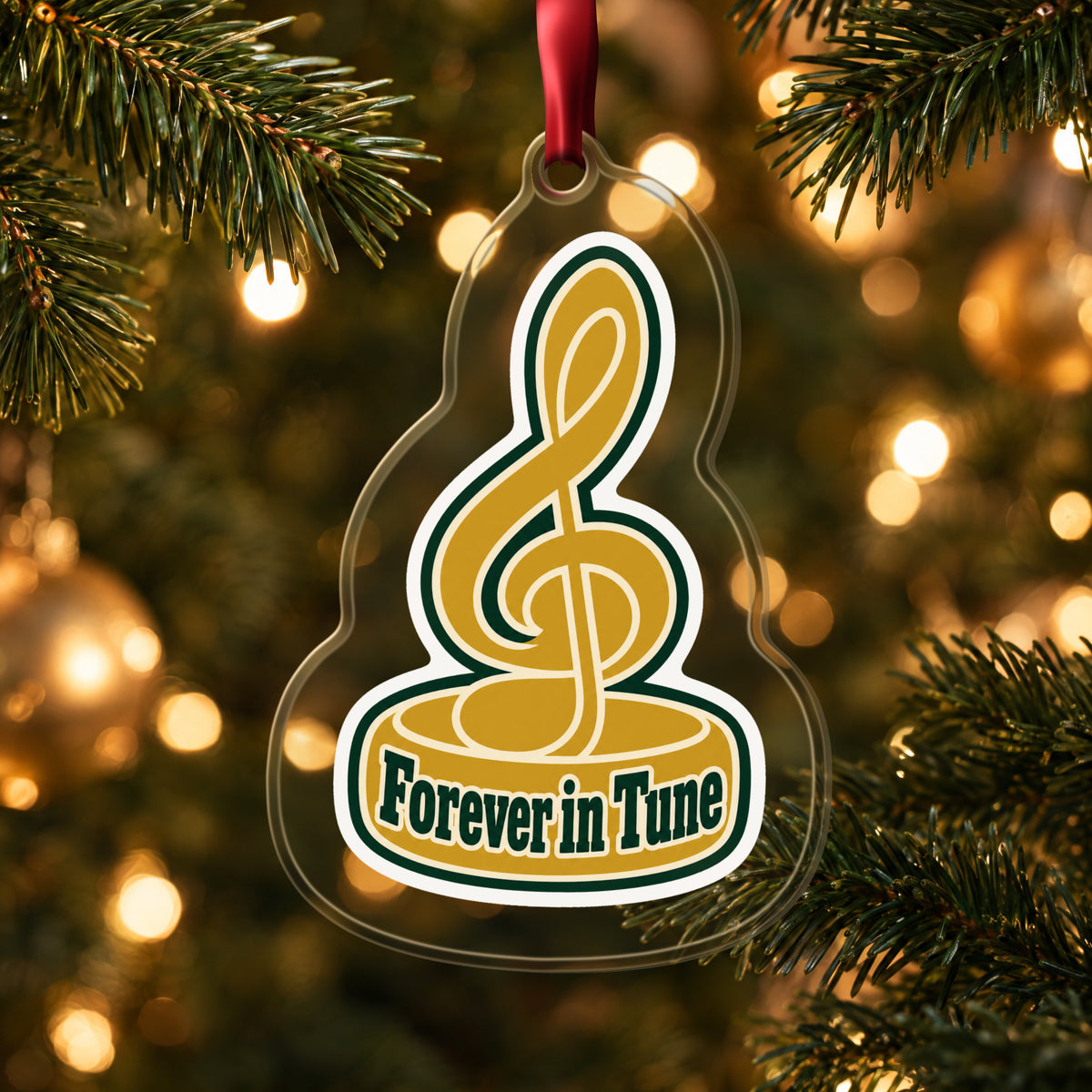 Forever in Tune Treble Clef clear acrylic Christmas ornament hanging on a lit Christmas tree with warm gold lights