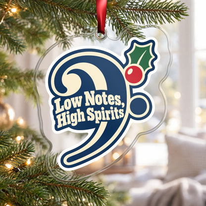 Low Notes, High Spirits Bass Clef clear acrylic Christmas ornament hanging on a Christmas tree by a bright window