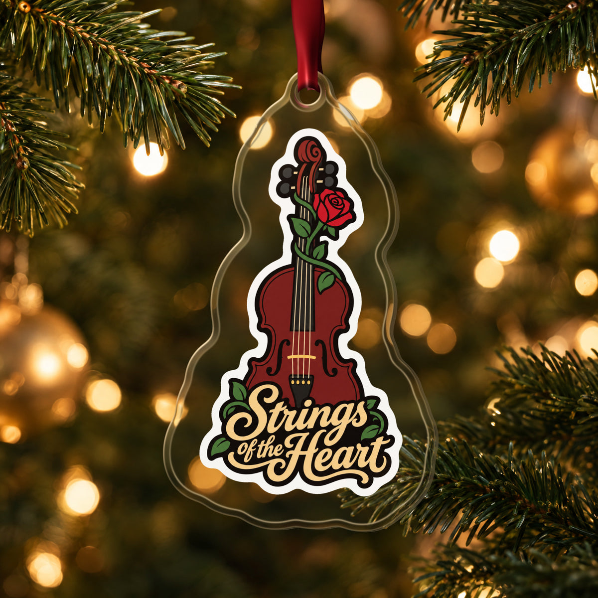 Strings of the Heart Violin clear acrylic Christmas ornament hanging on a lit Christmas tree with warm gold lights