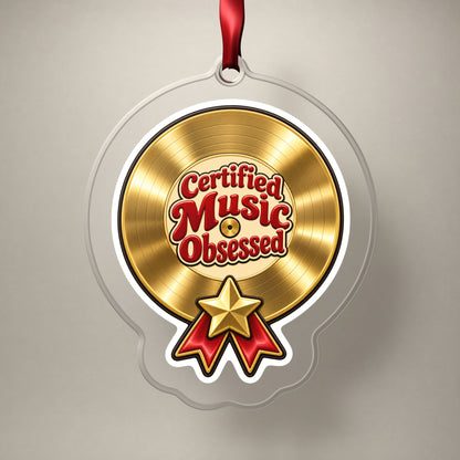 Certified Music Obsessed Gold Record clear acrylic Christmas ornament on a plain studio backdrop with its red ribbon