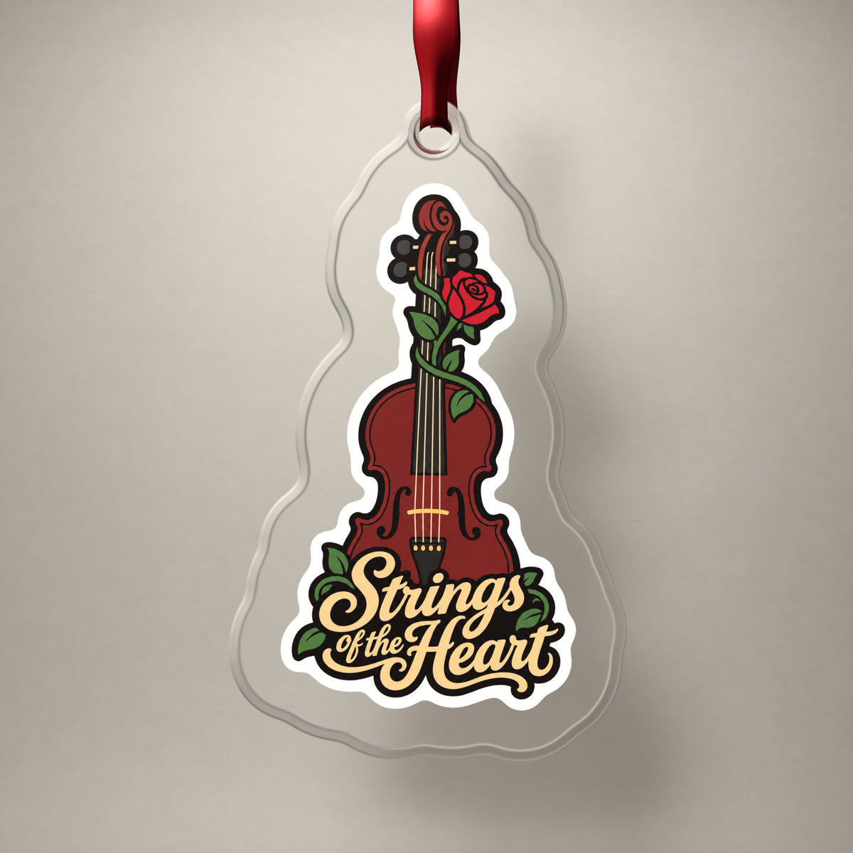 Strings of the Heart Violin clear acrylic Christmas ornament on a plain studio backdrop with its red ribbon