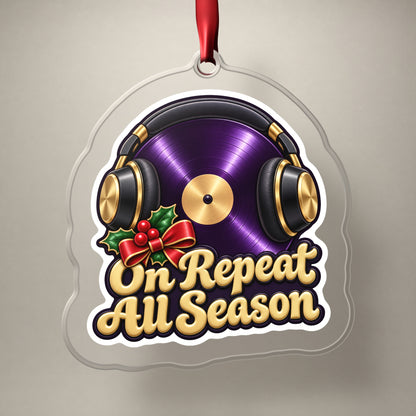 On Repeat Vinyl and Headphones clear acrylic Christmas ornament on a plain studio backdrop with its red ribbon