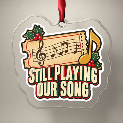 Still Playing Our Song Concert Ticket clear acrylic Christmas ornament on a plain studio backdrop with its red ribbon