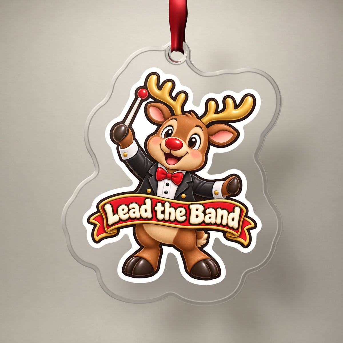 Lead the Band Reindeer Conductor clear acrylic Christmas ornament on a plain studio backdrop with its red ribbon