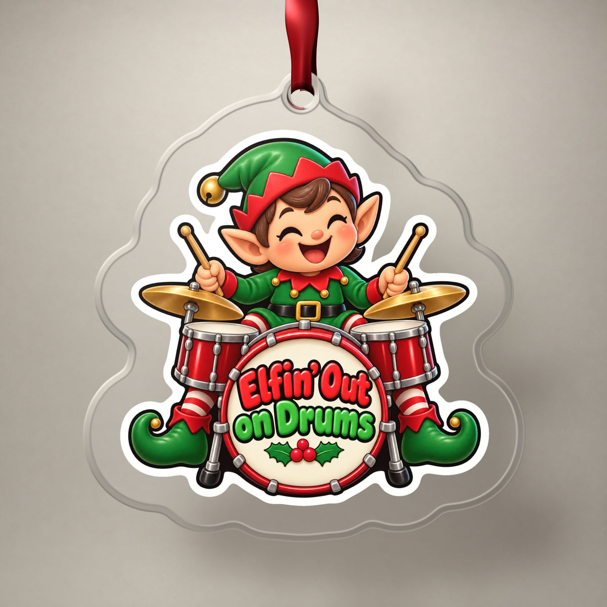Elfin' Out on Drums Elf Drummer clear acrylic Christmas ornament on a plain studio backdrop with its red ribbon