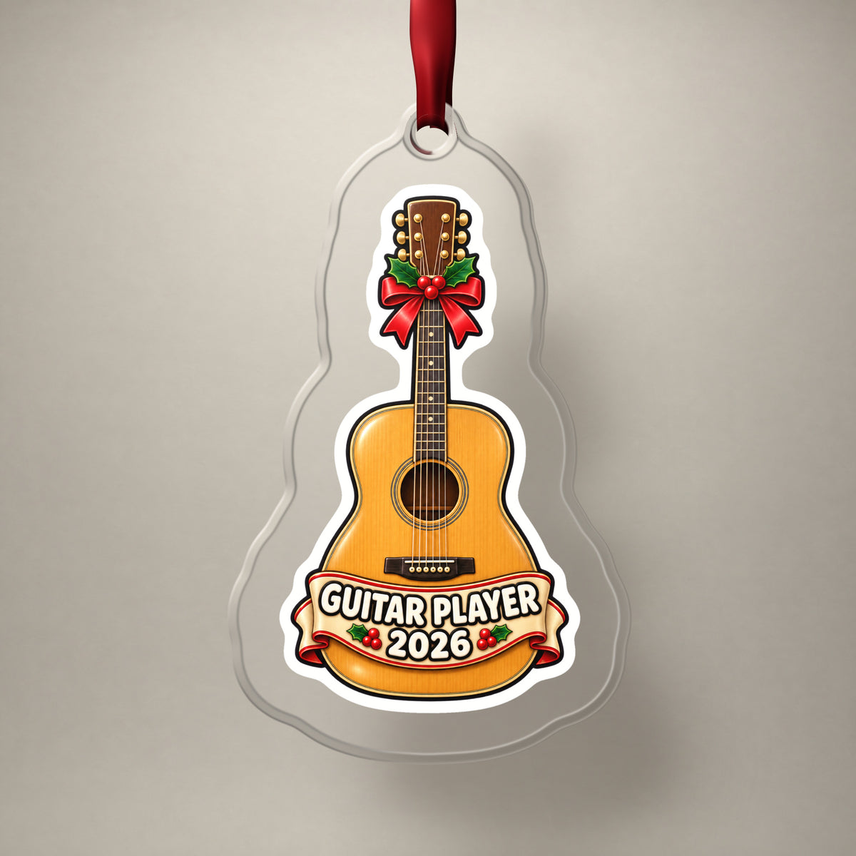 Guitar Player 2026 clear acrylic Christmas ornament on a plain studio backdrop with its red ribbon