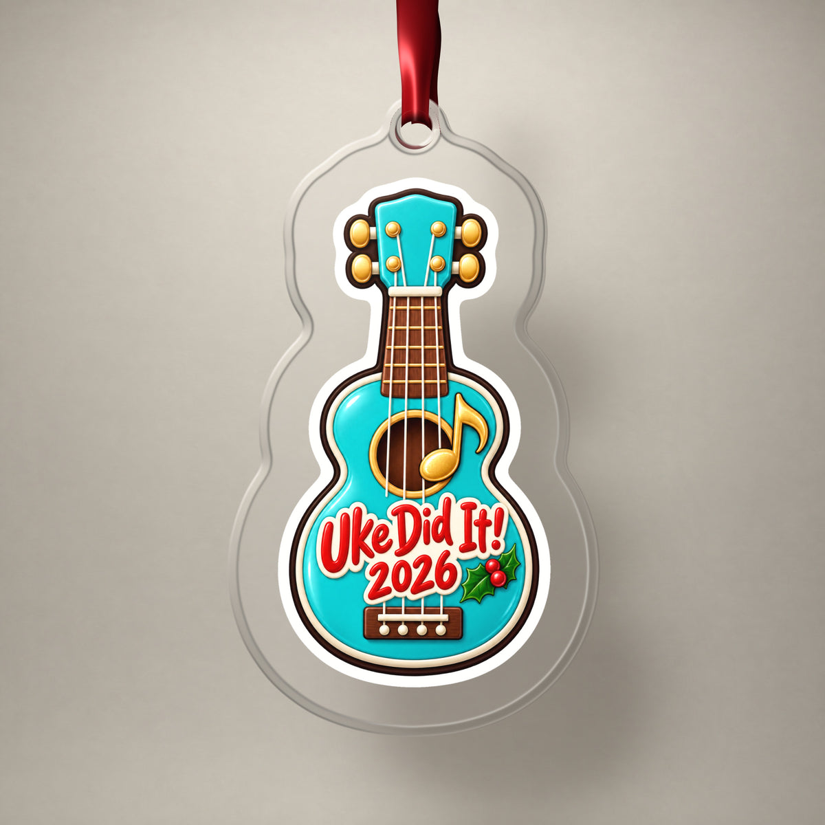 Uke Did It 2026 First Ukulele clear acrylic Christmas ornament on a plain studio backdrop with its red ribbon