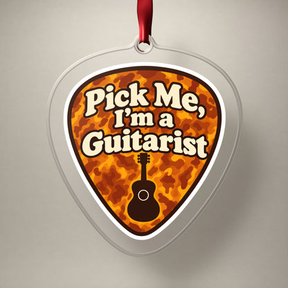 Pick Me, I'm a Guitarist Guitar Pick clear acrylic Christmas ornament on a plain studio backdrop with its red ribbon