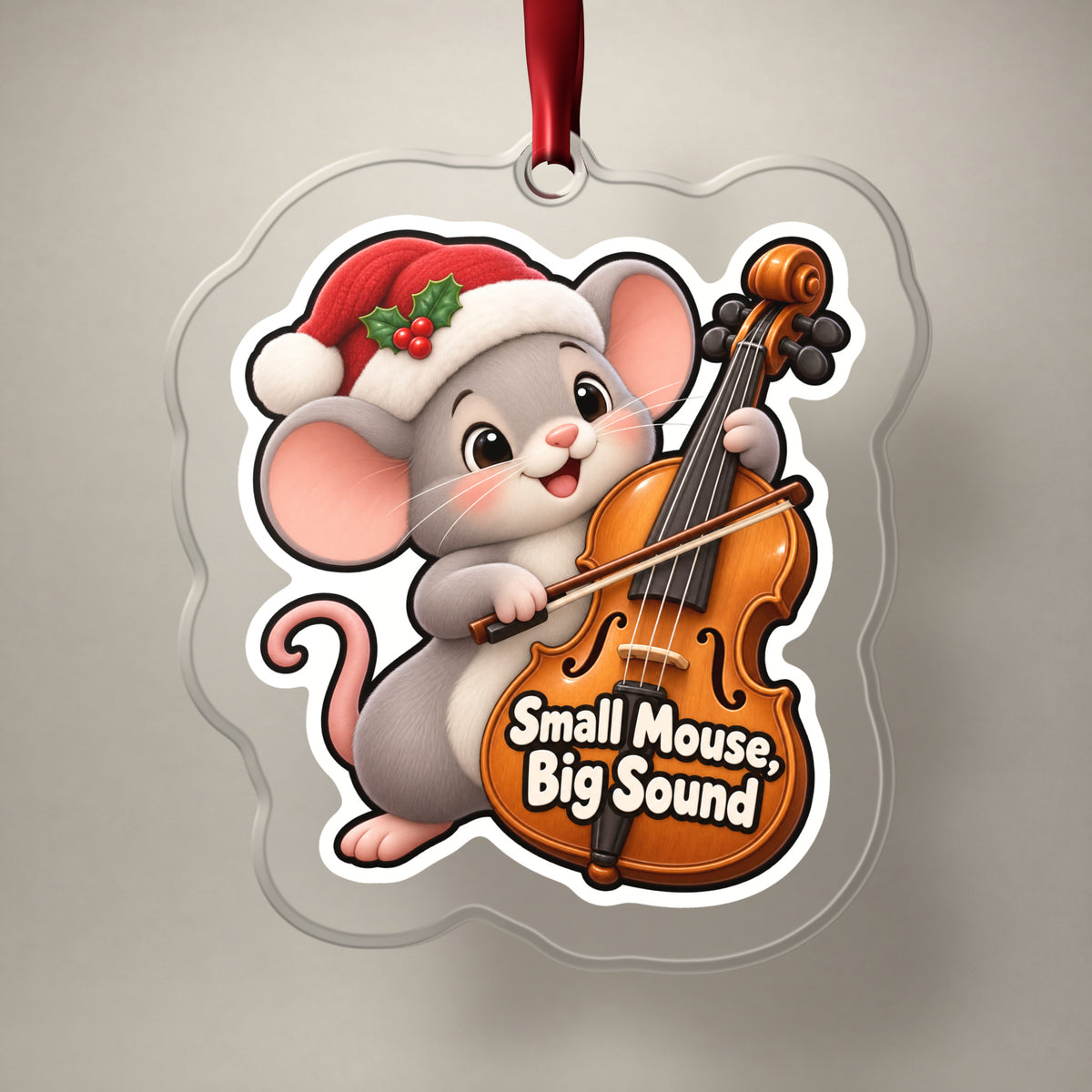 Small Mouse, Big Sound Cello clear acrylic Christmas ornament on a plain studio backdrop with its red ribbon