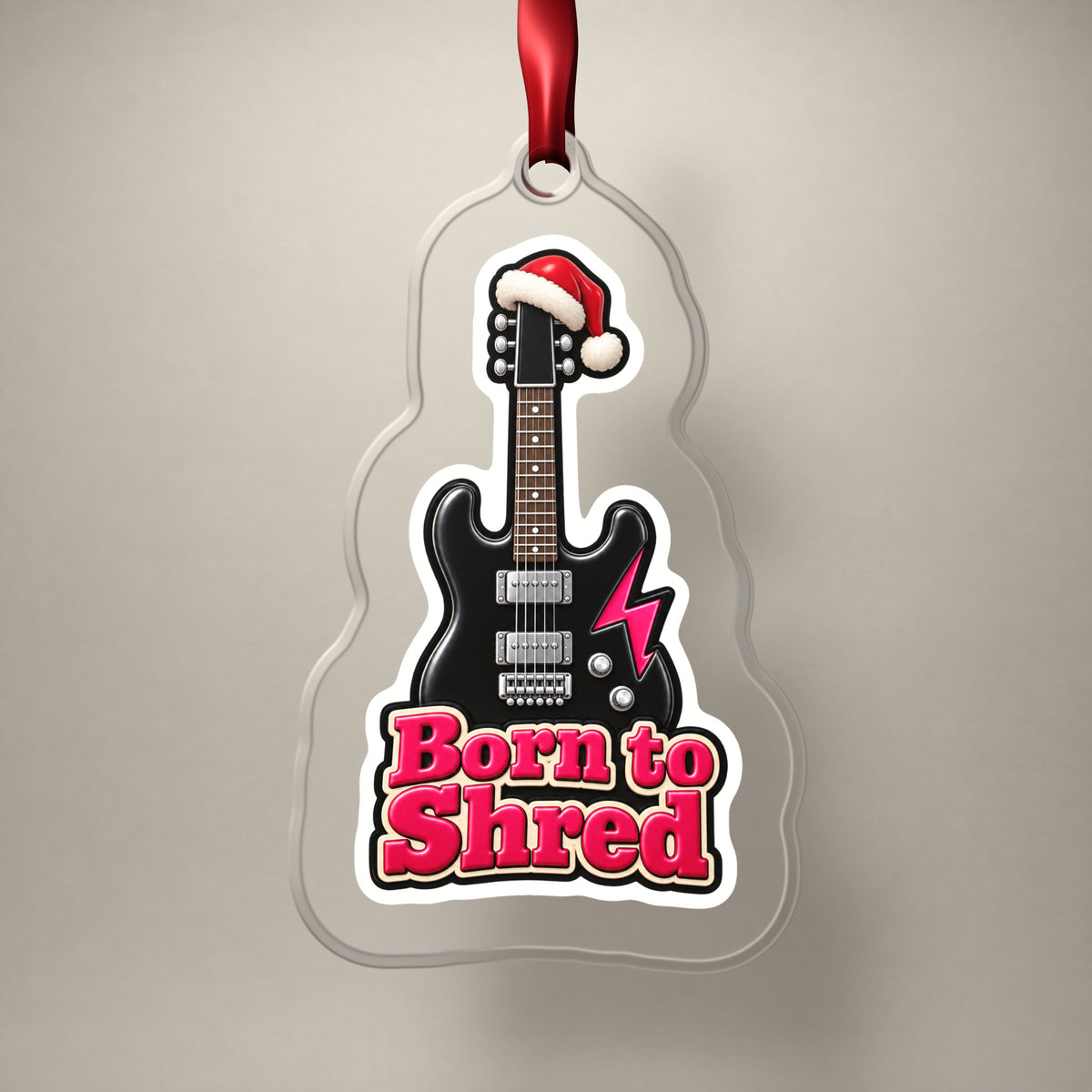 Born to Shred Electric Guitar clear acrylic Christmas ornament on a plain studio backdrop with its red ribbon