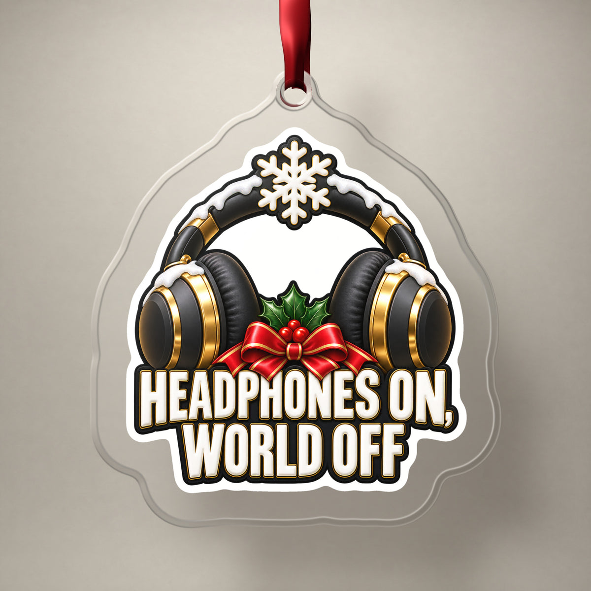 Headphones On, World Off clear acrylic Christmas ornament on a plain studio backdrop with its red ribbon
