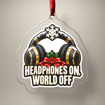 Headphones On, World Off clear acrylic Christmas ornament on a plain studio backdrop with its red ribbon