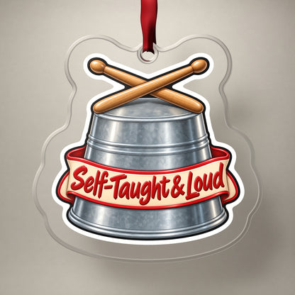 Self-Taught & Loud Bucket Drummer clear acrylic Christmas ornament on a plain studio backdrop with its red ribbon
