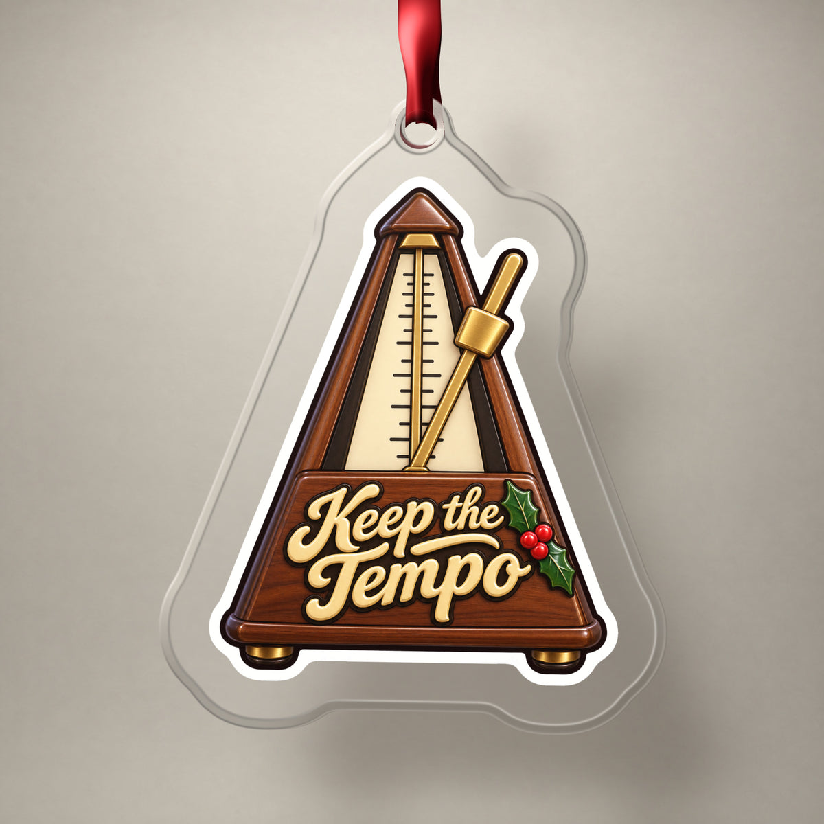 Keep the Tempo Metronome clear acrylic Christmas ornament on a plain studio backdrop with its red ribbon