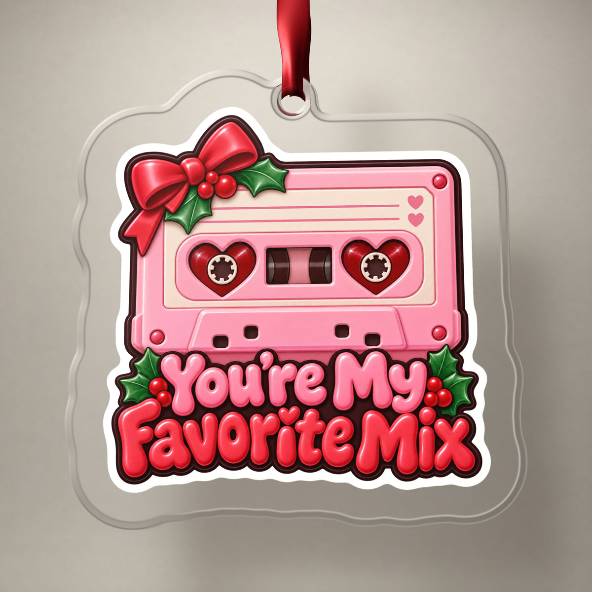You're My Favorite Mix Cassette clear acrylic Christmas ornament on a plain studio backdrop with its red ribbon