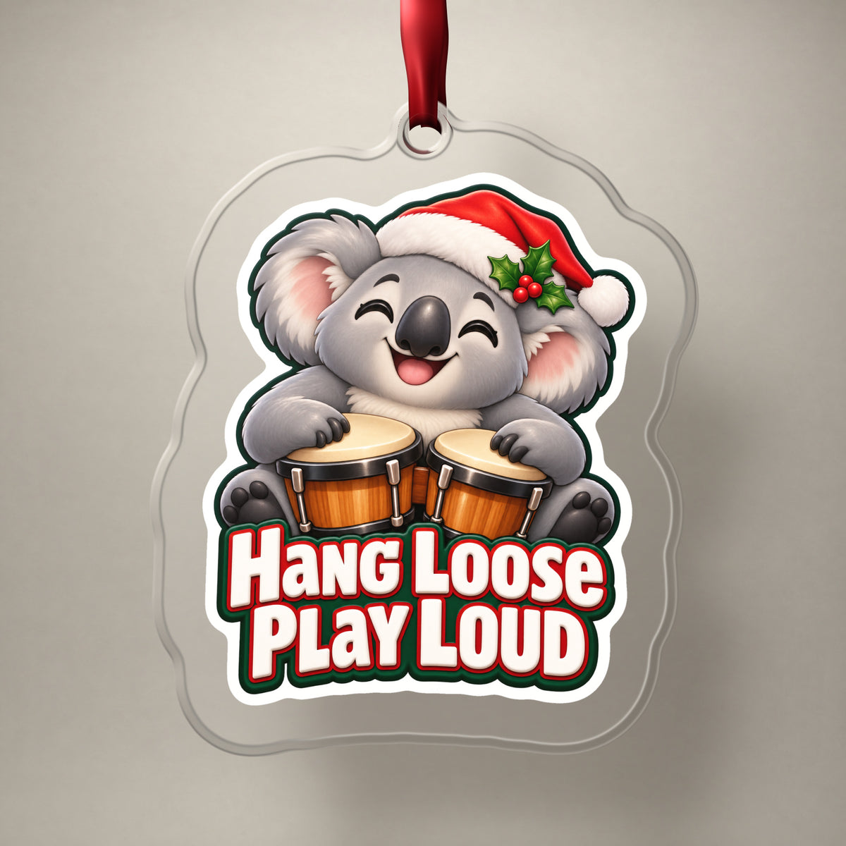 Hang Loose, Play Loud Koala Bongo clear acrylic Christmas ornament on a plain studio backdrop with its red ribbon
