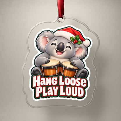 Hang Loose, Play Loud Koala Bongo clear acrylic Christmas ornament on a plain studio backdrop with its red ribbon