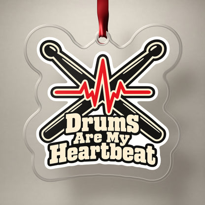 Drums Are My Heartbeat Drumsticks clear acrylic Christmas ornament on a plain studio backdrop with its red ribbon