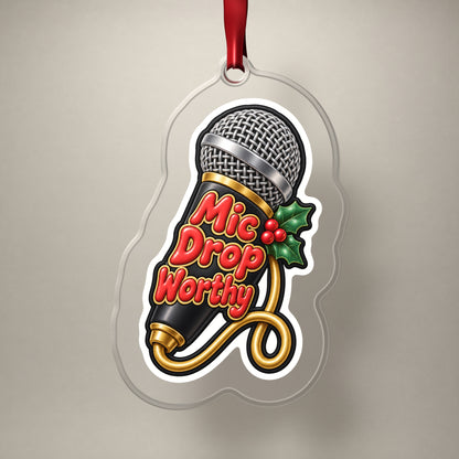 Mic Drop Worthy Microphone clear acrylic Christmas ornament on a plain studio backdrop with its red ribbon