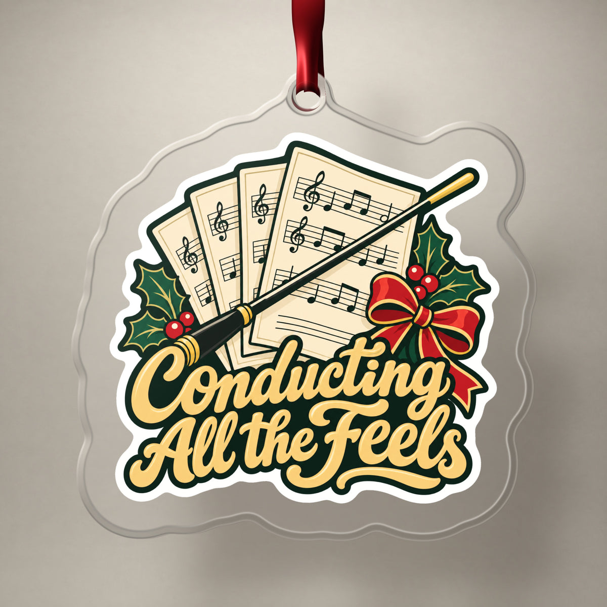 Conducting All the Feels Baton clear acrylic Christmas ornament on a plain studio backdrop with its red ribbon