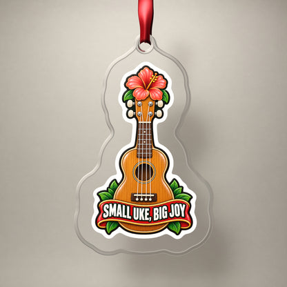 Small Uke, Big Joy Ukulele clear acrylic Christmas ornament on a plain studio backdrop with its red ribbon