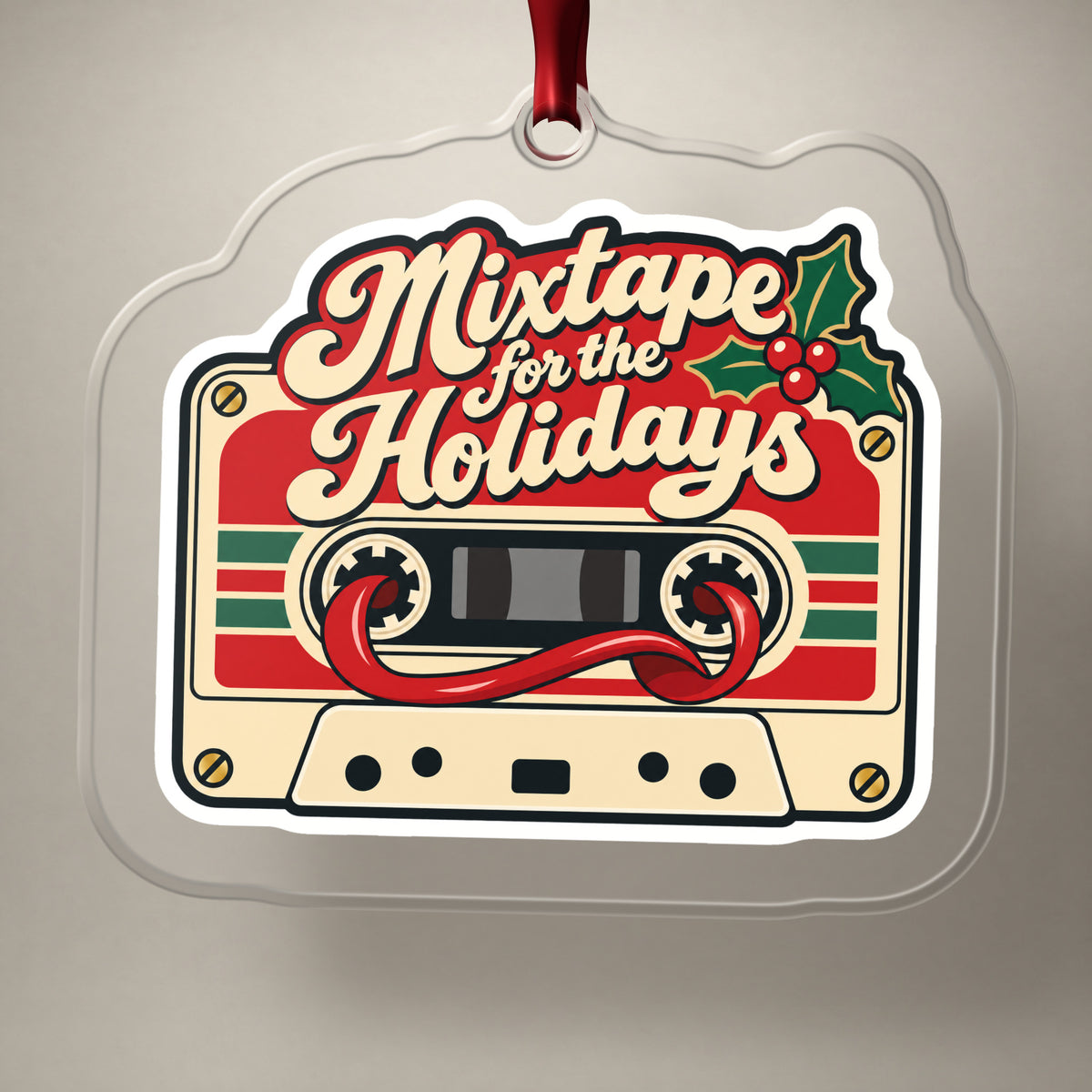 Mixtape for the Holidays Cassette clear acrylic Christmas ornament on a plain studio backdrop with its red ribbon