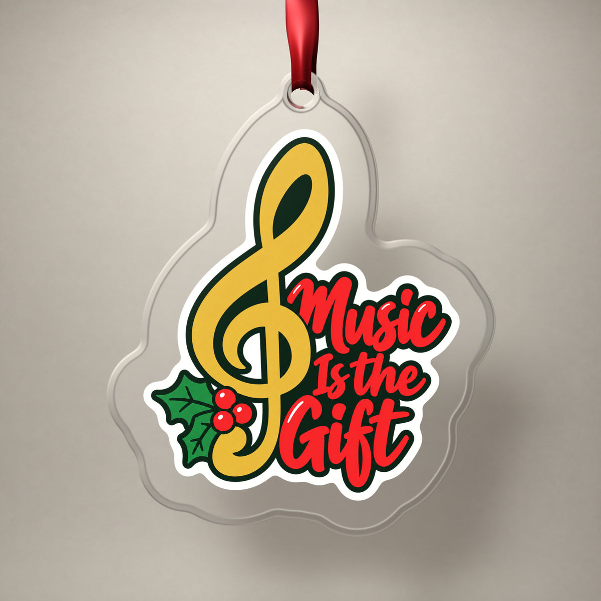 Music Is the Gift Treble Clef clear acrylic Christmas ornament on a plain studio backdrop with its red ribbon
