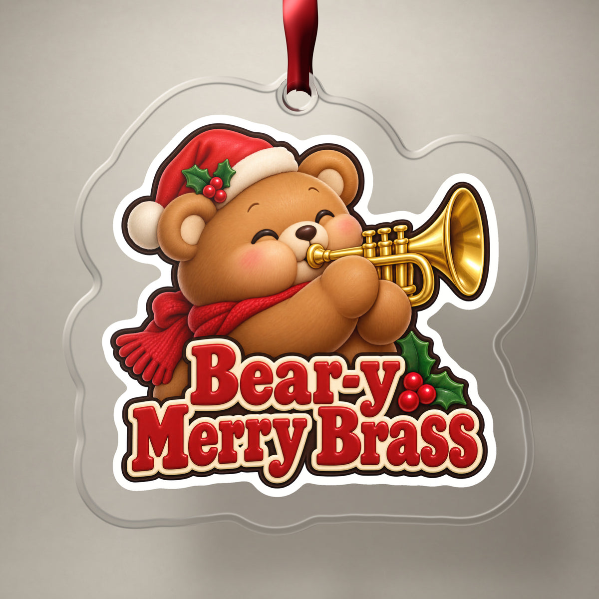 Bear-y Merry Brass Teddy Bear Trumpet clear acrylic Christmas ornament on a plain studio backdrop with its red ribbon