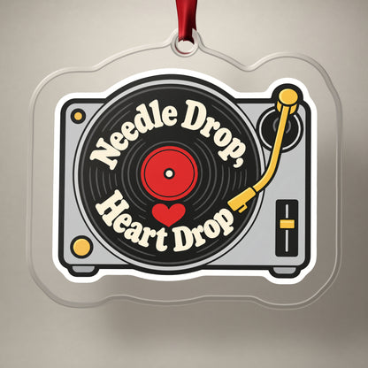 Needle Drop, Heart Drop Turntable clear acrylic Christmas ornament on a plain studio backdrop with its red ribbon