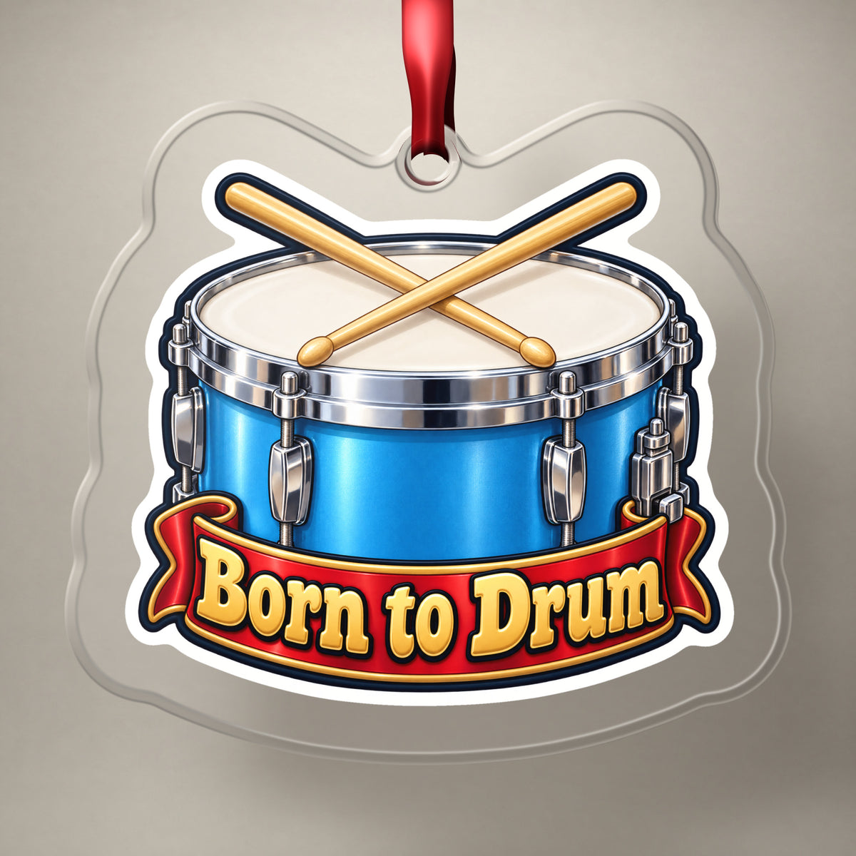 Born to Drum Snare Drum clear acrylic Christmas ornament on a plain studio backdrop with its red ribbon