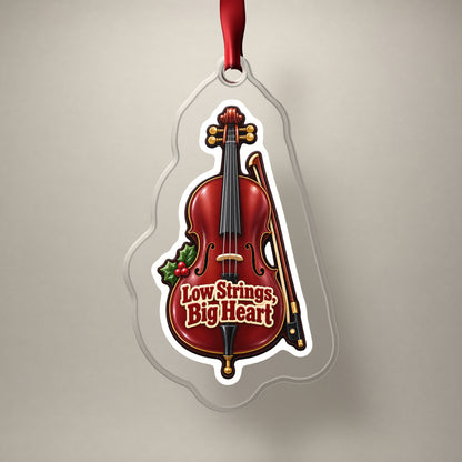 Low Strings, Big Heart Cello clear acrylic Christmas ornament on a plain studio backdrop with its red ribbon