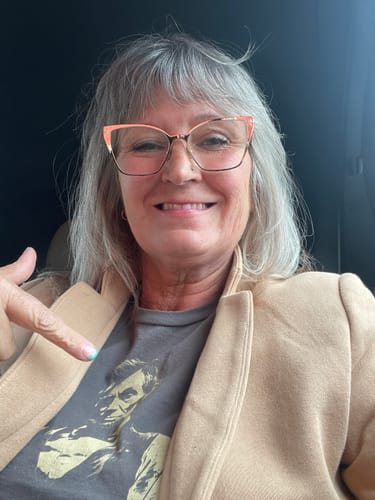 Karen S. smiling and pointing to the print on her grey Lincoln Guitar tee
